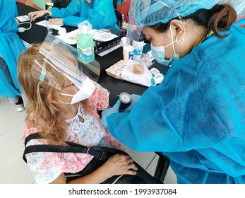 Las Pinas, Metro Manila, Philippines - June 2021: A Healthcare Worker In PPE Suit Checks The Blood Pressure Of A Senior Citizen Prior To Receiving The COVID-19 Vaccine.