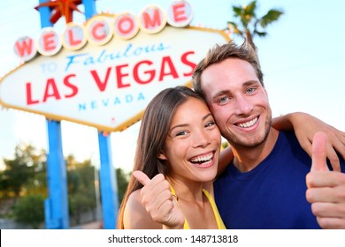 Las Vegas Couple Happy And Excited At Welcome To Fabulous Las Vegas Sign Billboard At The Strip. Young Multiracial People, Asian Woman And Caucasian Man Having Fun On Travel In Las Vegas, Nevada, USA.