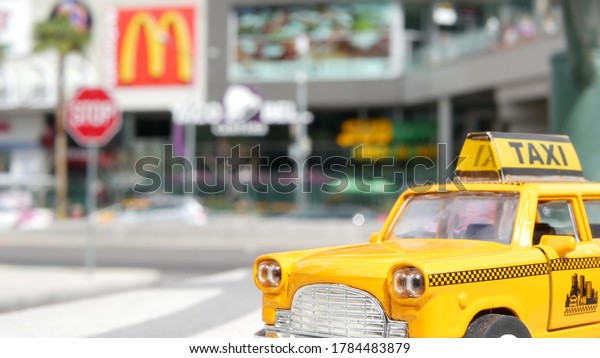 LAS VEGAS, NEVADA USA - 7 MAR 2020: Yellow vacant
mini taxi cab close up on Harmon avenue corner. Small retro car
model. Little iconic auto toy as symbol of transport against
american shopping mall.