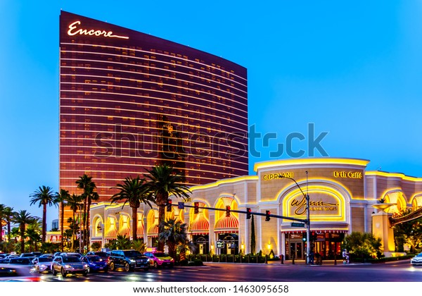 Las Vegas, Nevada/USA - June 8, 2019: Evening at\
the modern building with tinted glass walls of the Encore Wynn\
Resort and Casino on Las Vegas Blvd, The Strip, with the Wynn Plaza\
Shops in neon lights