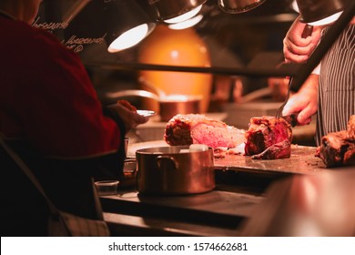 Las Vegas, NV 11/28/2019 — Chef Cutting Roast Beef And Prime Rib To Serve The Customers Holding Plates In Line. Captured At The Grand Buffet In MGM Grand On Thanksgiving Day.