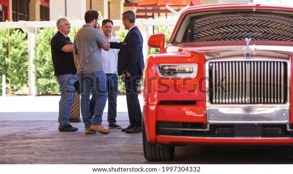 Las Vegas, NV 6-25-2021: Chauffeur driver of
Resort World’s house car greets his group of VIP passengers with a
handshake. Brand new 2021 Rolls-Royce Phantom captured in bokeh.
Driveway of Conrad.