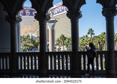 Las Vegas, NV - November 24, 2021: Sihouette Of A Woman Checking Her Phone At The Famous Venetian Hotel And Casino, With The Mirage In The Distance.