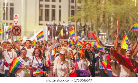 Las Vegas, NV, USA 10/11/2019 — Participants of all genders march in the Pride Parade on Fremont Street on National Coming Out Day. People cheerfully waving LGBTQ PRIDE rainbow flags.