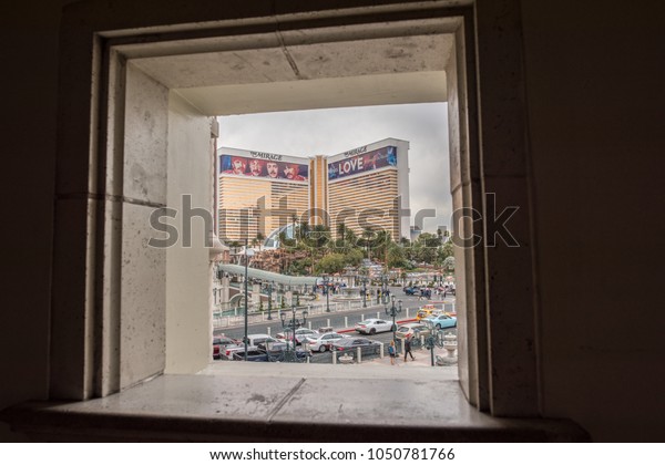 Las Vegas, NV / USA - March 7, 2018: The Mirage\
Hotel and Casino visible in the distance through the frame of a\
stone window at the Venetian across the street.  Both hotels are\
popular and famous.