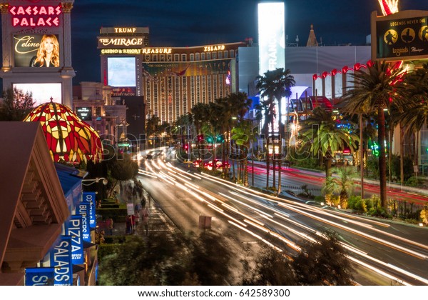 Las Vegas, USA - Circa 2017: Long exposure light\
trail of busy street night Las Vegas Blvd strip Traffic pass famous\
hotel casino resorts lit neon light advertisement. Caesars, Mirage,\
Treasure Island