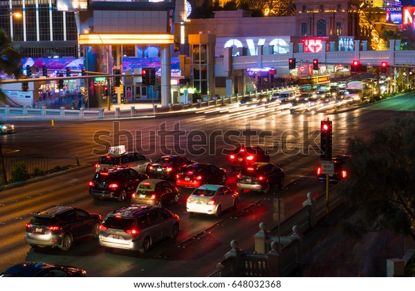 Las Vegas,\
USA - Circa 2017: Long exposure light trails of Las Vegas Blvd\
traffic at busy intersection. Taxi wait at red light and car zoom\
by. CVS Pharmacy store sign in\
background