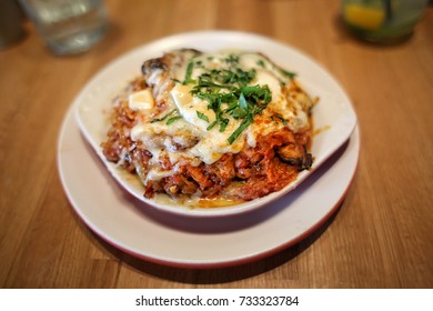 Lasagna Bolognese Organic Cuisine In White Dish At Farm To Table Restaurant On Wooden Tabletop