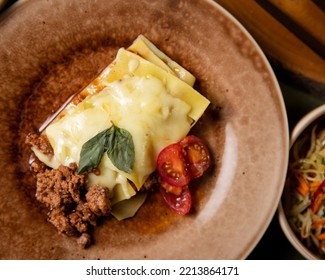 Lasagna With Ground Beef And Melted Chees On A Brown Plate And Green Background.  Traditional Dish. Italian Cuisine