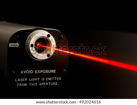 Laser beam from lab laser. Warning notice on front. Aperture is not noisy, it looks this way due to diffraction of coherent light at aperture boundary. Beam made visible by mist sprayed into air.