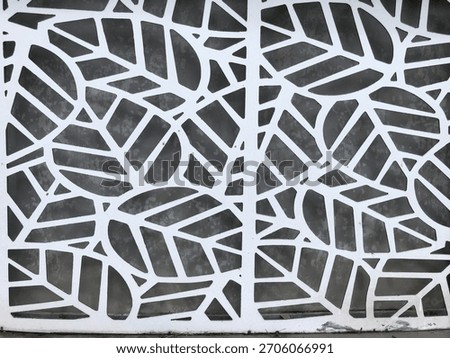 A laser cut design of an abstract pattern of white leaves and twigs, inspired by nature, on a dark background.