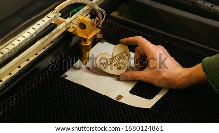Laser cutting beam high precision on a plywood sheet. Modern technology of wood cutting. laser cut wooden 3d symbol of valentine's day.  Industrial laser engraving. CNC laser. Masterclass, workshop 