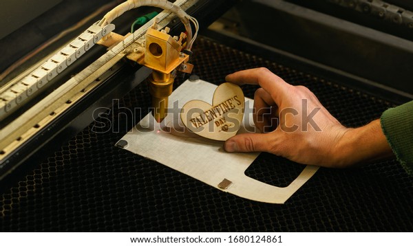 Laser cutting beam high precision on a plywood sheet.\
Modern technology of wood cutting. laser cut wooden 3d symbol of\
valentine\'s day.  Industrial laser engraving. CNC laser.\
Masterclass, workshop 