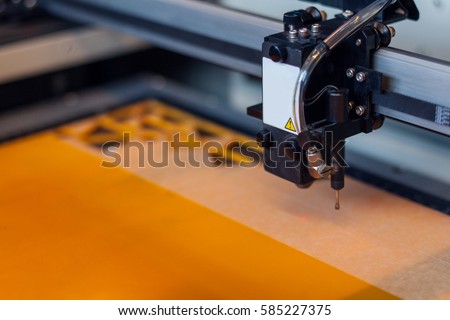 Laser cutting. Laser cutter machine and orange acrylic sheet cut with geometric shapes.