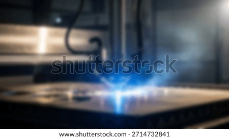 Laser cutting machine in action with producing sparks and fumes in a factory.
