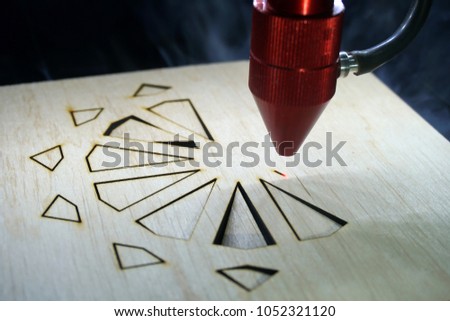 Laser cutting machine in process of cutting plywood decorative star.