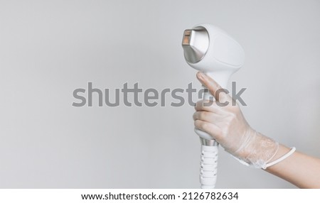 Laser device for removing unwanted hair in the hand of nurse. Laser hair removal, cosmetic body treatments. Concept of hygiene, beauty, health. Girl holding a working part of the epilator in her hand