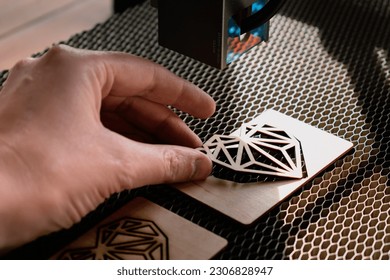 Laser engraving and cutting, woman holding an example of a cut out wooden heart