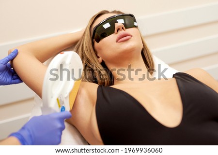 Laser hair removal, photoepilation, body and skin care concept. young woman remove hair on armpits at cosmetology clinic. close up shot, hygiene procedure concept