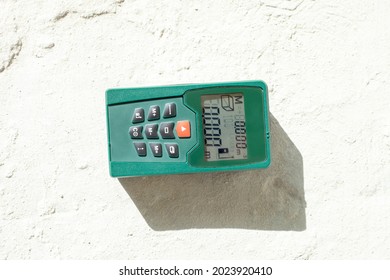 Laser rangefinder on cement floor. Laser distance meter laying on concrete floor. Close up measuring device in house. Worker using electronic range finder on building, measure concept