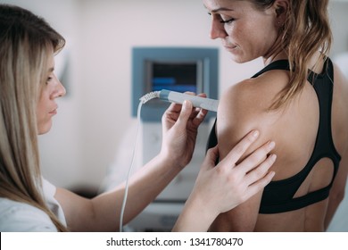 Laser therapy. Physical therapist treating patient's shoulder - Powered by Shutterstock