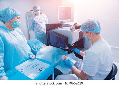 Laser vision correction. A patient and team of surgeons in the operating room during ophthalmic surgery. Eyelid speculum. Lasik treatment. Patient under sterile cover