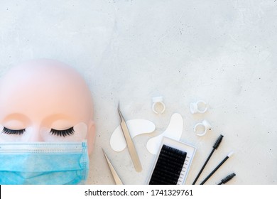 Lash Artist Theme Beauty Background.  Training Mannequin Head With Strip Lashes And Protective Mask.  Treatment Products Displayed In Flat Lay Style.  Plain Background With Copy Text Space.