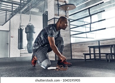 Last details. Handsome young African man in sport clothing tying his shoe while exercising in the gym - Powered by Shutterstock