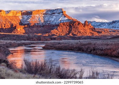 The last golden light of sunset hits the mesa near red rocks of Fisher Towers, in front of the La Sal Mountains with fresh snow blowing off the peaks, near Moab, Utah. - Powered by Shutterstock