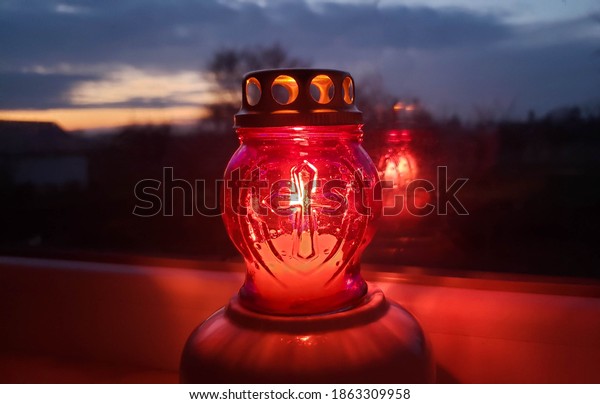Last light on the sunset. All\
Saints Day candle. Burning single red candle light on dark\
background. In memory of concept and pray for. Remembrance for\
family.