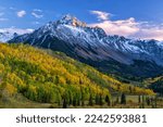 The last light of the setting sun hits the crags atop Mount Sneffels, with a mostly golden grove of quaking aspens below, in the San Juan Mountains near Ridgway, Colorado.