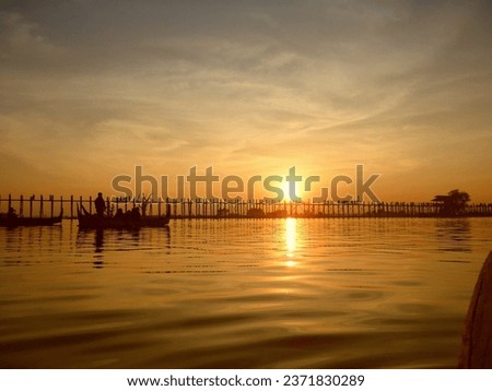 Last light at U Beng Bridge, wooden bridge in Mandalay, Myanmar, Wonderful orange sun set scenery with silhouette of people walking across the bridge with twilight sky background