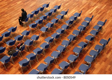 Last man waiting with rows of empty chair behind him.