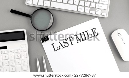 LAST MILE written on paper with office tools and keyboard on grey background