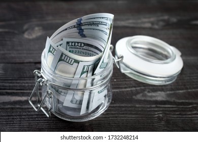 Last Money - Dollar Bills In A Glass Jar On A Wooden Table. Concept Of Saving Money. Stock For A Rainy Day