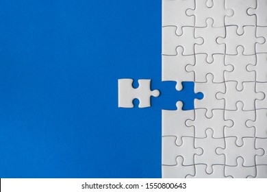 The last piece of white jigsaw puzzle on blue paper