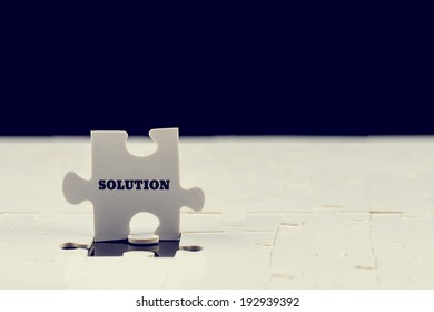 Last puzzle piece with the word - Solution - standing upright on top of a jigsaw puzzle with just the one piece missing to complete it, toned instagram effect. - Shutterstock ID 192939392