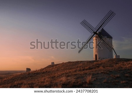 The last rays of the sun bathe a beautiful old windmill in Castilla La Mancha, a place of inspiration for Cervantes to locate Don Quixote. Spanish tourism concet.