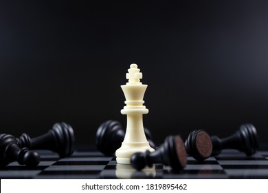 Last Standing White King Chess Piece Among Other Falling Black Chess Pieces