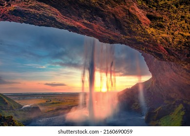 Last sunlight flowing of Seljalandsfoss waterfall, where tourists can walk behind the falling waters. Astonishing summer scene of Iceland, Europe. Beauty of nature concept background.