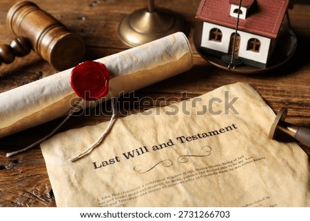 Last Will and Testament, gavel, scroll and house model on wooden table, closeup