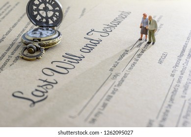 Last will and testament  legacy, inheritance or death tax concept : Miniature elder  old couple stands on a legal document form, depicts preparing to transfer properties to their heirs after death