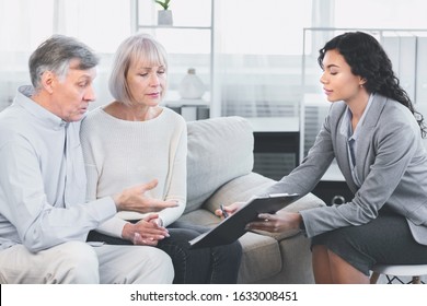 Last Will And Testament. Mature man sitting on couch embracing wife, asking about document, signing papers with consultant