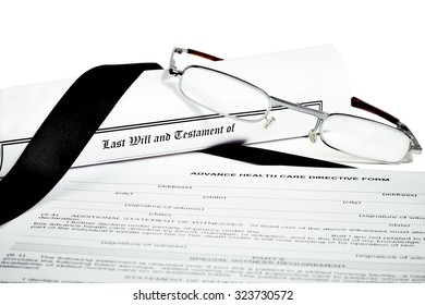 Last Will And Testament Rolled Up With Reading Glasses Isoated On White With A Black Ribbon And Advance Health Care Directive