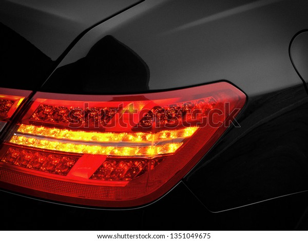 Last-minute lights and brake lights are\
shot in close-up on a black passenger car.\
Fragment