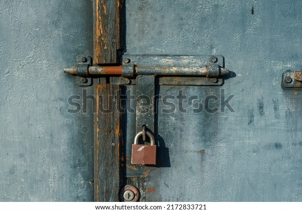 latch on garage\
door with padlock. old metal garage door closed with a padlock. \
Anti-burglary padlock on the gate. with door-handles and latch and\
hinges. Abandoned locked\
gate