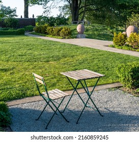 Late afternoon shadows around a wooden table and chair in Mellon Park, a city park in Pittsburgh, Pennsylvania, USA on a sunny spring day