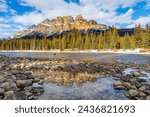 Late afternoon sun reflects off the majestic Castle Mountain in Banff National Park, Canada, with reflection on snow-melted puddle along the Bow River.
