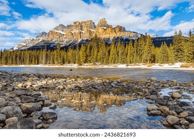 Late afternoon sun reflects off the majestic Castle Mountain in Banff National Park, Canada, with reflection on snow-melted puddle along the Bow River. - Powered by Shutterstock