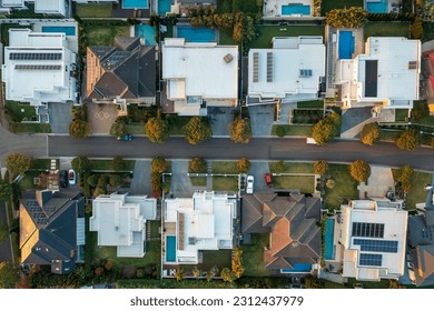 Late afternoon top down aerial view of modern upmarket houses with pools and rooftop solar in outer suburban Sydney, Australia